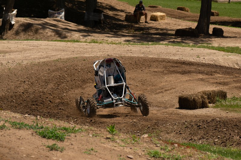 Baja car sliding through a dirt turn on a dynamic event course