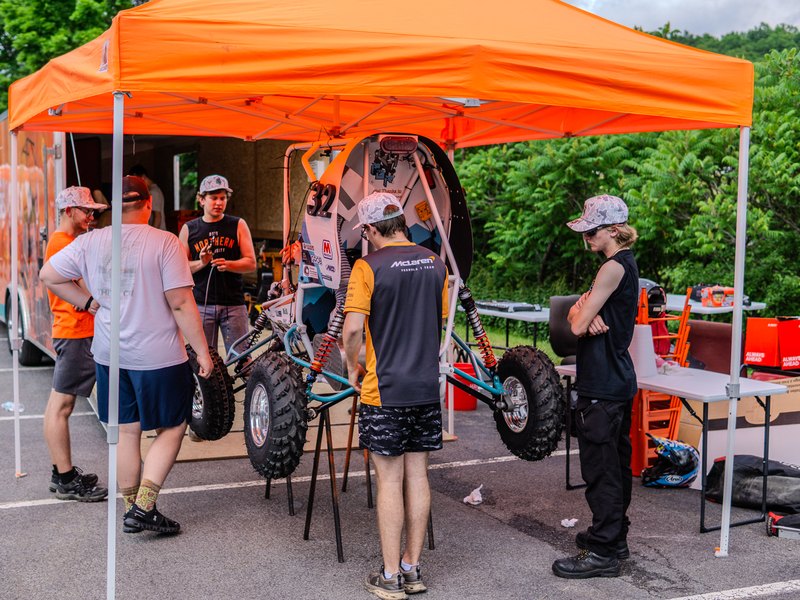 A Baja team working on their car under an orange pit tent