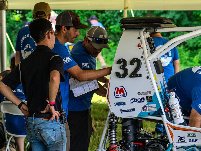 Technical inspectors with checklists going over Baja car number 32