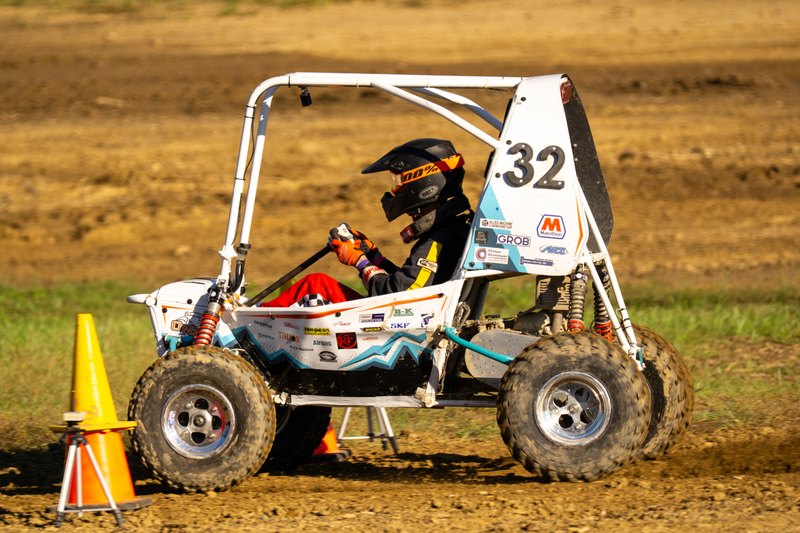 Side profile of Baja car number 32 on dirt beside a cone, number panel readable
