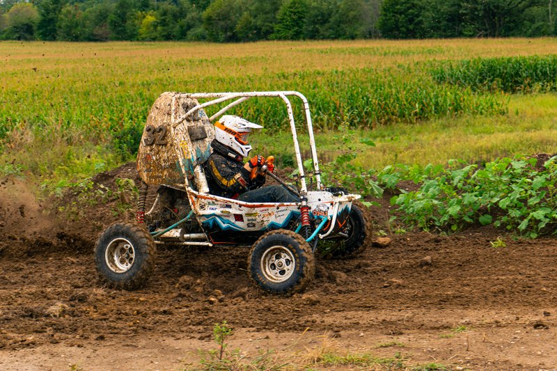 Baja car number 32 driving through a dirt section beside a cornfield