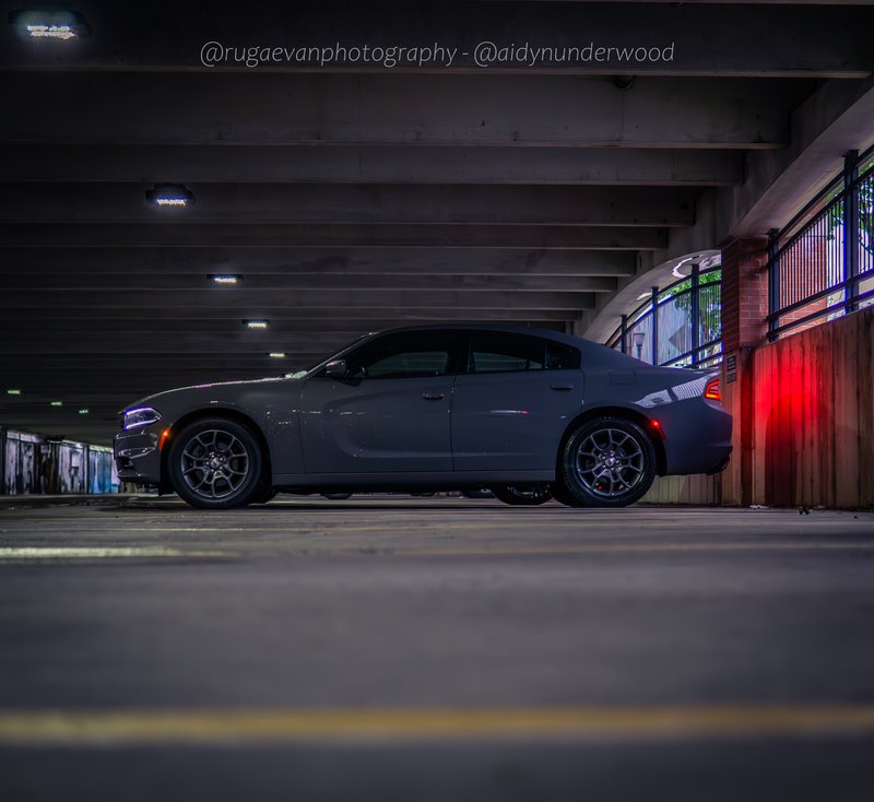 Dark muscle car in a concrete parking garage at night