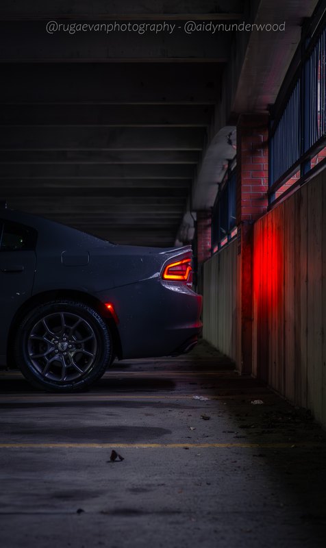 Dark muscle car in a concrete parking garage at night