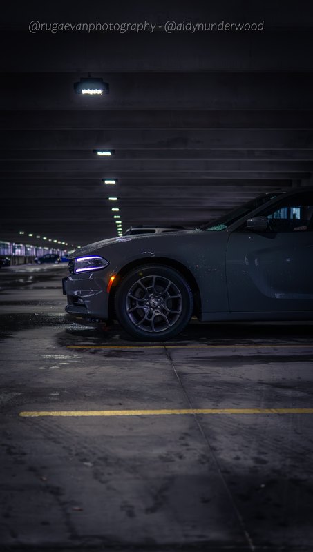Dark muscle car in a concrete parking garage at night