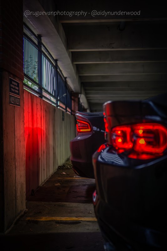 Dark muscle car in a concrete parking garage at night