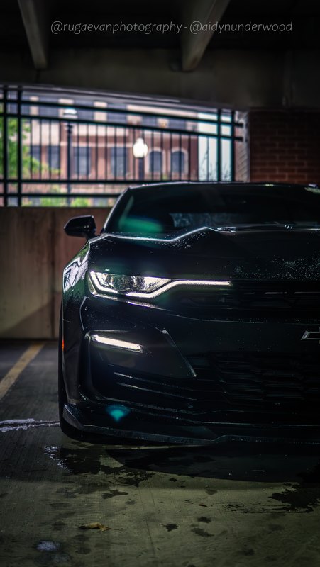 Dark muscle car in a concrete parking garage at night