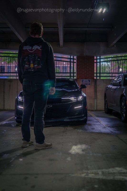 Dark muscle car in a concrete parking garage at night