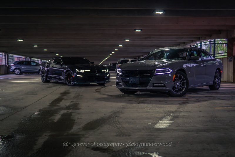 Dark muscle car in a concrete parking garage at night