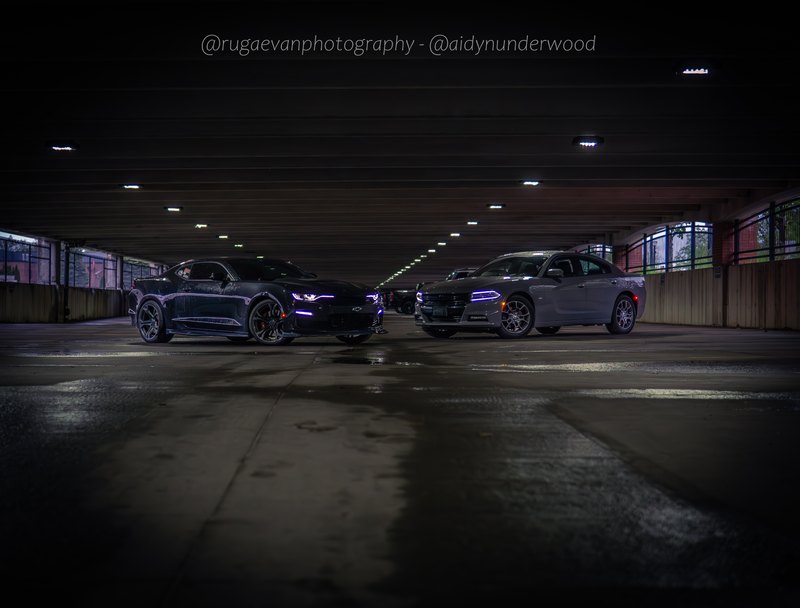Dark muscle car in a concrete parking garage at night