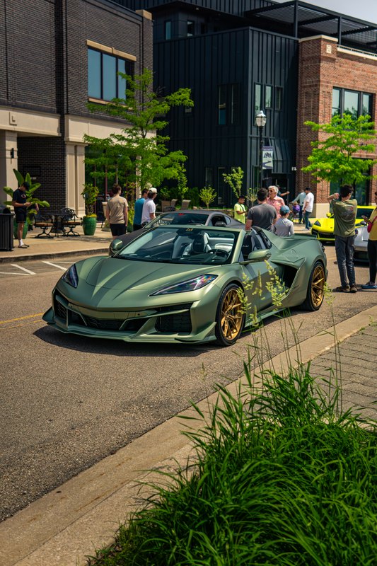 Green mid-engine Corvette convertible parked on a downtown street at a car show